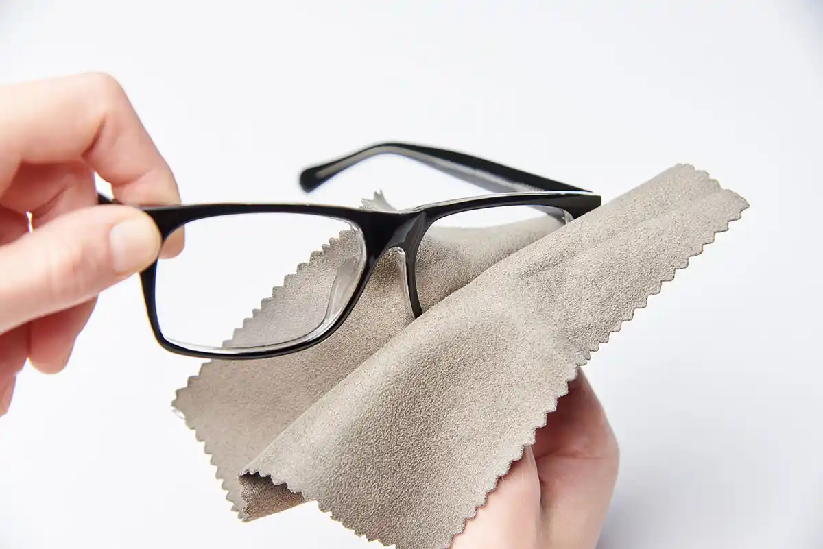 Mann reinigt seine Brille sorgfältig mit einem Brillenputztuch
